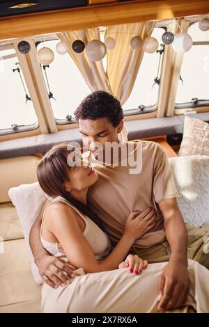 Ein Mann und eine Frau, ein interrassisches Paar, sitzen eng zusammen auf einer Couch, tief im Gespräch, genießen einen romantischen und intimen Moment. Stockfoto