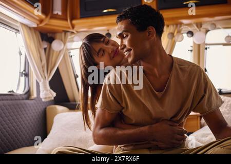 Ein Mann und eine Frau sitzen friedlich auf einem Bett und schaffen einen ruhigen und intimen Moment in ihrer gemütlichen Umgebung. Stockfoto