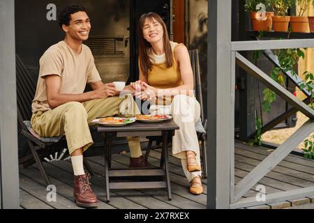 Ein Mann und eine Frau verschiedener Rassen sitzen friedlich auf einer Veranda und genießen sich in einer ruhigen Umgebung. Stockfoto