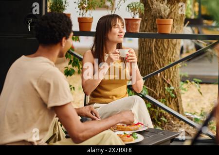 Ein Mann und eine Frau genießen einen friedlichen Moment auf einer Bank und genießen Tassen Kaffee in Gesellschaft. Stockfoto
