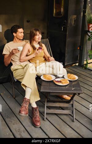 Ein Mann und eine Frau, die friedlich zusammen auf einer Veranda sitzen und sich in einer ruhigen Umgebung amüsieren. Stockfoto