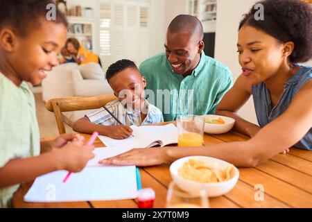 Familie Drinnen Zu Hause Hilft Kindern Bei Hausaufgaben Mit Großeltern Im Hintergrund Stockfoto