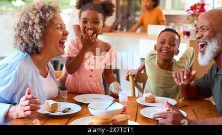 Großeltern Mit Enkelkindern Zuhause Dekorieren Kuchen Zusammen Mit Familie Im Hintergrund Stockfoto