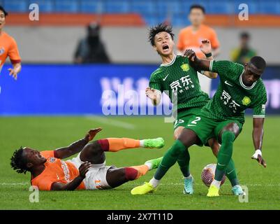 Qingdao, Chinas Provinz Shandong. Mai 2024. Jiang Wenhao (C) von Peking Guoan streitet mit Martin Boakye (L) von Qingdao Hainiu während des 13. Runde Spiels zwischen Qingdao Hainiu und Peking Guoan in der Chinesischen Super League 2024 in Qingdao, ostchinesischer Provinz Shandong, 21. Mai 2024. Quelle: Li Ziheng/Xinhua/Alamy Live News Stockfoto