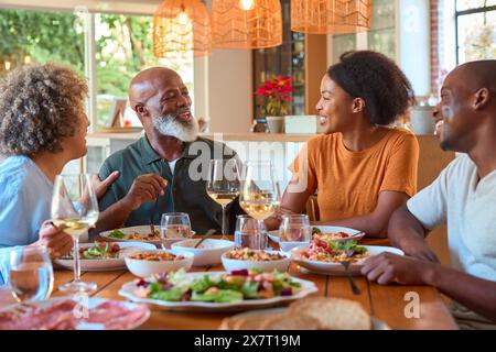 Senioreneltern Rund Um Den Tisch Essen Mit Wein Zu Hause Mit Erwachsenem Sohn Und Tochter Stockfoto