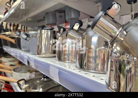 Verschiedene Töpfe und Pfannen ordentlich in einer Reihe auf einem Regal in einer Küche angeordnet. Stockfoto