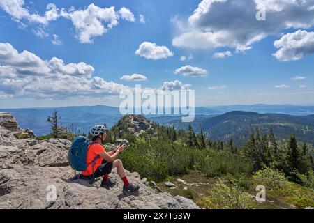 Aktive Seniorin auf einer Fahrradtour mit ihrem E-Mountainbike im felsigen Gipfel des Großen Arbers im Bayerischen Wald, Bayern, Ger Stockfoto