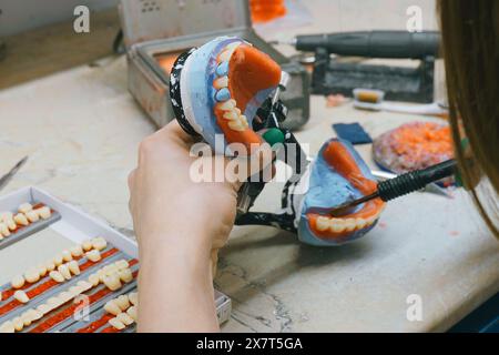 Ein Zahntechniker wird beim Löten, Schmelzen und Formen eines Zahns für Prothesen mit Händen in Nahaufnahme mit Werkzeugen und Geräten gesehen. Stockfoto