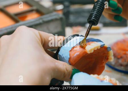 Ein Zahntechniker arbeitet sorgfältig an der Herstellung von Prothesen mit speziellen Werkzeugen und Techniken, um Präzision und Qualität zu gewährleisten. Stockfoto