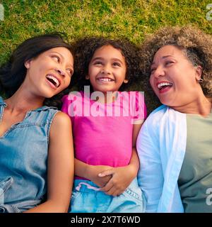 Blick Hinunter Auf Die Weibliche Familie Der Drei Generationen, Die Lacht Und Auf Dem Gras Liegt, Auf Dem Land Stockfoto
