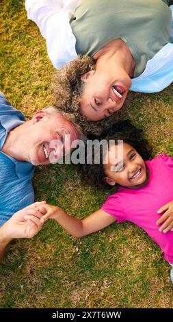 Auf Multi Racial Großeltern Mit Enkelin, Die Draußen Auf Gras Liegt Stockfoto