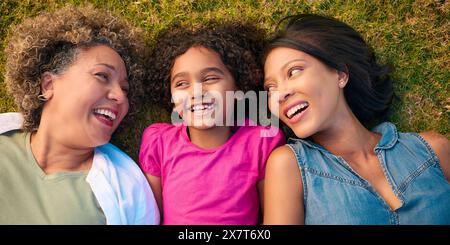 Blick Hinunter Auf Die Weibliche Familie Der Drei Generationen, Die Lacht Und Auf Dem Gras Liegt, Auf Dem Land Stockfoto