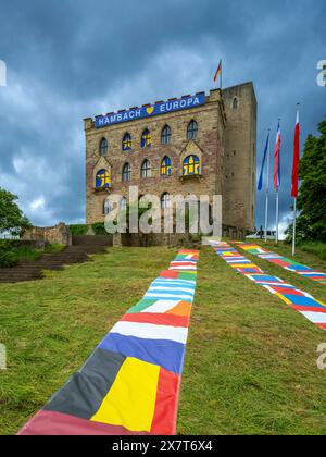 Das Hambacher Schloss mit europäischen Fahnen auf dem Rasen vor dem Schloss, transparent mit der Aufschrift Hambach Europa an der Schlossmauer und gelbe Sternen auf blauem Grund in den Fenstern. Vom 23. bis 26. Mai 2024 wird dort und in der Altstadt von Neustadt a.d. Weinstraße das fest der Demokratie feiern. Änd. 27. Mai 1832 kam bis zu 30,000 Menschen auf dem Hambacher Schlossberg zusammen, um für ein geeintes Deutschland, politische Grundrechte und ein solidarisches verbundenes Europa eintreten. Wegen des 1832 dort ausgerichteten Hambacher Festes gilt es neben der Frankfurter Paulskirche Stockfoto