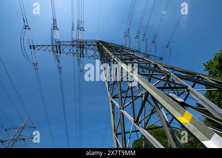 Ein großer elektrischer Turm mit vielen Drähten und Kabeln, der hoch vor einem blauen Himmel steht. Stockfoto