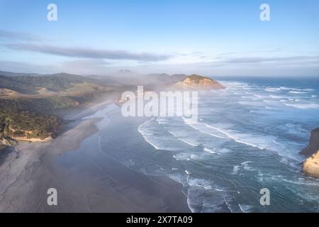 Blick aus der Vogelperspektive auf den malerischen Sonnenaufgang, der über dem Strand von Wharariki und den Bogenway-Inseln auf der Tasmanischen See im Westen von cape Farewell, Neuseeland, strahlt Stockfoto