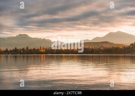 Wunderschöne Landschaft mit goldenem Sonnenaufgang über Bergketten und Herbstwald am Lake Wanaka in Neuseeland Stockfoto