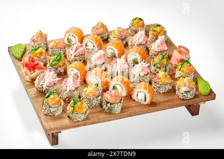 Köstliches Set knuspriger Tempura-Brötchen mit verschiedenen Belägen und Lachsbrötchen aus Philadelphia, serviert auf Holztablett mit scharfem Wasabi und eingelegtem Ingwer. Stockfoto