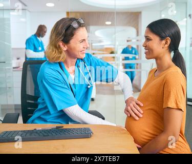Krankenschwester Oder Arzt Mit Scrubs, Die Schwangere Frau In Der Klinik Für Geburtshilfe Des Krankenhauses Untersuchen Stockfoto