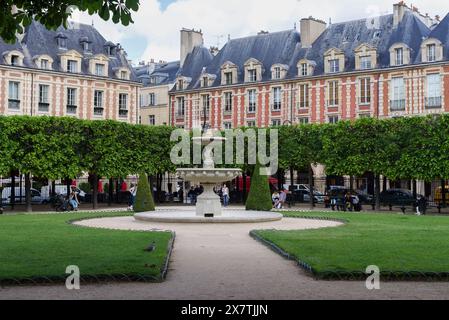 Paris, Frankreich 05.16.2024 Brunnen am Place de Vosges (Place Royale), die Gäste entspannen sich an einem warmen Frühlingstag Stockfoto