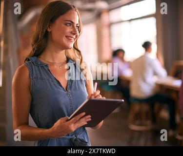 Geschäftsfrau Mit Digitalem Tablet Und Stylus Pen Arbeitet Im Büro Mit Kollegen Im Hintergrund Stockfoto