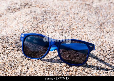 Sonnenbrille mit blauen Gläsern am Strand. Am Strand an einem hellen sonnigen Tag Stockfoto