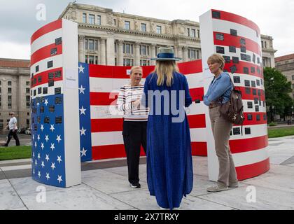 Washington, USA. Mai 2024. Die Künstlerin Suzanne Brennan Firstenber spricht mit den Besuchern während ihrer Kunstinstallation „Aliable Right to Life“ am 19. Mai 2024 im Freedom Plaza in Washington DC. Die Installation zeigt eine massive amerikanische Flagge, die aus den Namen von 1.039 Massenvernichtungsopfern entstand und ein Bild der Unabhängigkeitserklärung überlagert. Weitere Elemente sind ein Originalgedicht, das sich an alle Opfer von Waffengewalt richtet, und ein kreisförmiges Wandgemälde, auf dem Besucher persönliche Geschichten erzählen können. (Foto: Probal Rashid/SIPA USA) Credit: SIPA USA/Alamy Live News Stockfoto