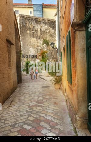 Kotor, Montenegro - 20. September 2023: Abendliche enge Straße der Altstadt, Inschrift Stadt Namensschild auf der Fassade, Menschen Stockfoto