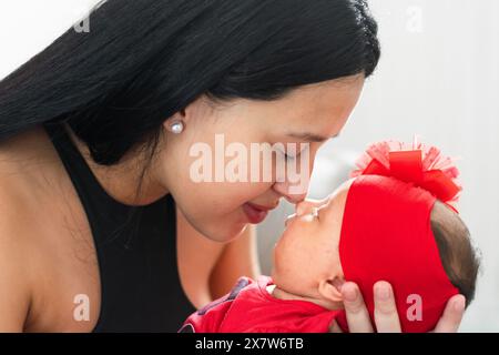 Junge Latina-Frau, die ihre Nase an die Nase ihres neugeborenen Babys legt, glücklich und stolz, Mutter zu sein. Stockfoto