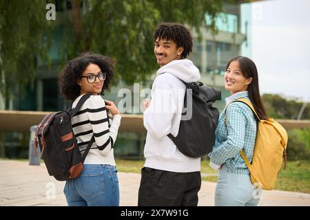 Drei junge Schüler stehen zusammen, jeder trägt einen Rucksack Stockfoto