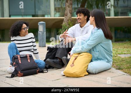 Drei junge Menschen sitzen mit Rucksäcken auf dem Boden Stockfoto