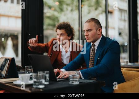 Zwei Geschäftsleute arbeiten in einem modernen Café an einem Laptop zusammen Stockfoto