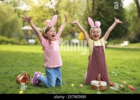 Osterfeier. Süße kleine Mädchen in Hasenohren jagen Eier draußen Stockfoto