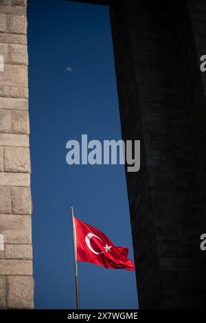 Nahaufnahme der türkischen Flagge, die vor einem klaren blauen Himmel winkt, mit dem Mond im Hintergrund. Stockfoto