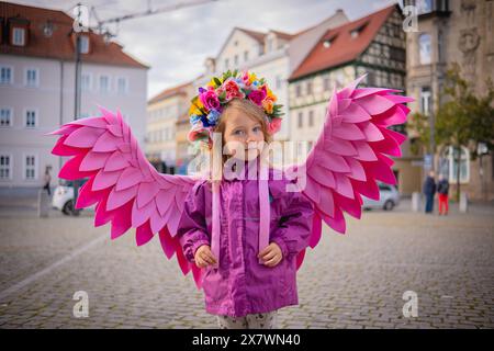 Schönes Mädchen mit rosafarbenen Engelsflügeln. Kleines süßes Mädchen in rosa Jacke und rosa handgefertigten Flügeln. Stockfoto