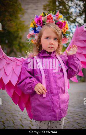 Schönes Mädchen mit rosafarbenen Engelsflügeln. Kleines süßes Mädchen in rosa Jacke und rosa handgefertigten Flügeln. Stockfoto