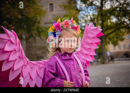 Schönes Mädchen mit rosafarbenen Engelsflügeln. Kleines süßes Mädchen in rosa Jacke und rosa handgefertigten Flügeln. Stockfoto