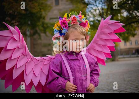 Schönes Mädchen mit rosafarbenen Engelsflügeln. Kleines süßes Mädchen in rosa Jacke und rosa handgefertigten Flügeln. Stockfoto