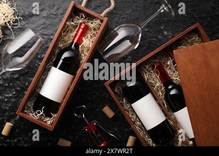 Flache Lagenkomposition mit Flaschen Wein in Holzkisten auf dunkel strukturiertem Tisch Stockfoto