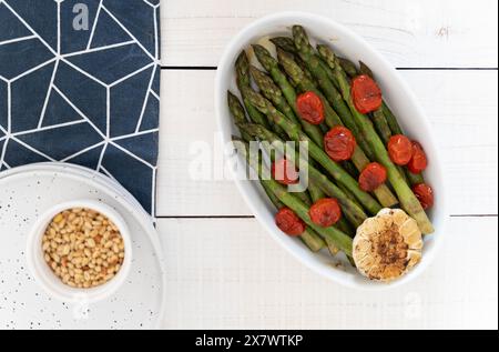 Grüner Spargel in weißem Tablett gebacken und als verzehrfertige Beilage serviert. Sie stellen eine Quelle für hervorragende Ballaststoffe dar. Stockfoto