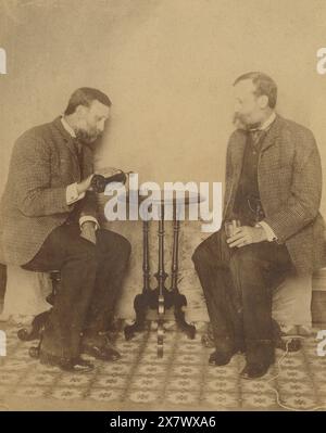 Antikes Foto von 1890, Brüder trinken zusammen Whiskey. Sie sind sieben Jahre voneinander entfernt, aber sehen aus wie Zwillinge. Genaue Lage unbekannt, wahrscheinlich Massachusetts oder Rhode Island, USA. QUELLE: ORIGINALFOTO Stockfoto