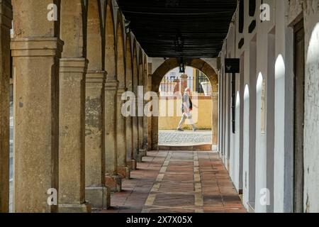 Ein Mann läuft an der Bogenarkade am Arcos Antiguo Claustro Santo Domingo in Ronda, Provinz Malaga, Spanien vorbei. Stockfoto