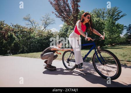 Junge Freunde, die einen sonnigen Tag im Park genießen, Frau auf dem Fahrrad und Mann auf dem Skateboard Stockfoto