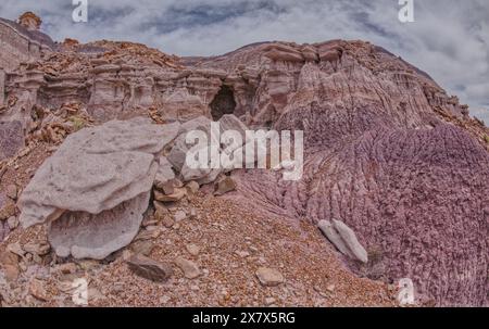 Eine flache Wasserfallhöhle, die von der Bentonitklippe unterhalb der Südseite von Blue Mesa im Petrified Forest National Park Arizona gemeißelt wurde. Stockfoto