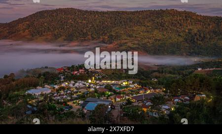 Eine Touristenattraktion in Thailand namens Khao Kho wird bei Sonnenaufgang mit Nebel über einem kleinen Dorf, der Provinz Phetchabun in Thailand, abgebildet. Stockfoto