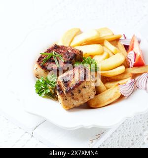Gebratene Schweinerippchen mit Pommes frites und frischen Tomaten. Heller Hintergrund. Kopierbereich. Stockfoto