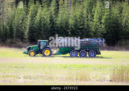 John Deere 7230R-Traktor und Samson PG-Schlammpanker auf Stoppelfeldern zur Injektion von Gülle zur Düngung. Paimio, Finnland. Mai 2024. Stockfoto