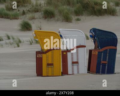 Nahaufnahme von drei bunten Liegen an einem leeren Strand, bunten Liegen am Strand und in den Dünen unter bedecktem Himmel am Meer, Jui Stockfoto