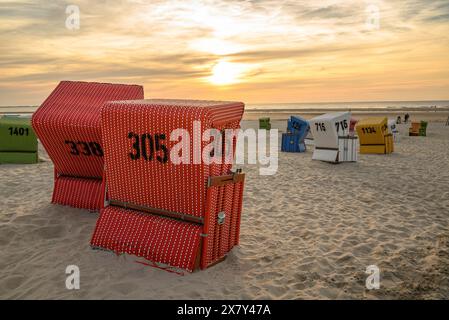 Mehrere Liegen am Strand bei Sonnenuntergang, Fokus auf rote Körbe, viele bunte Liegen an einem warmen Sommerabend am Meer, langeoog, deutschland Stockfoto