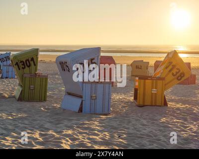 Bunte Liegen am Sand bei Sonnenuntergang, Sonnenuntergang an einem ruhigen Strand mit vielen bunten Liegen, warmes Abendlicht am Meer, L Stockfoto