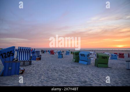 Liegestühle am Strand bei Sonnenuntergang, Fokus auf blaue Körbe, viele bunte Liegen an einem warmen Sommerabend am Meer, langeoog, deutschland Stockfoto